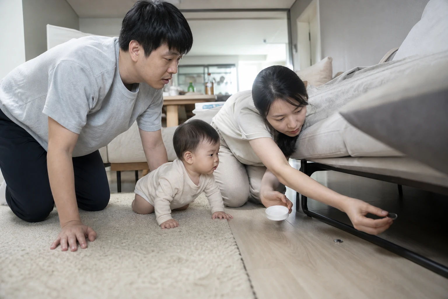 A photorealistic scene with an awake mobile baby and attentive adults practicing safe floor movement or checking home hazards