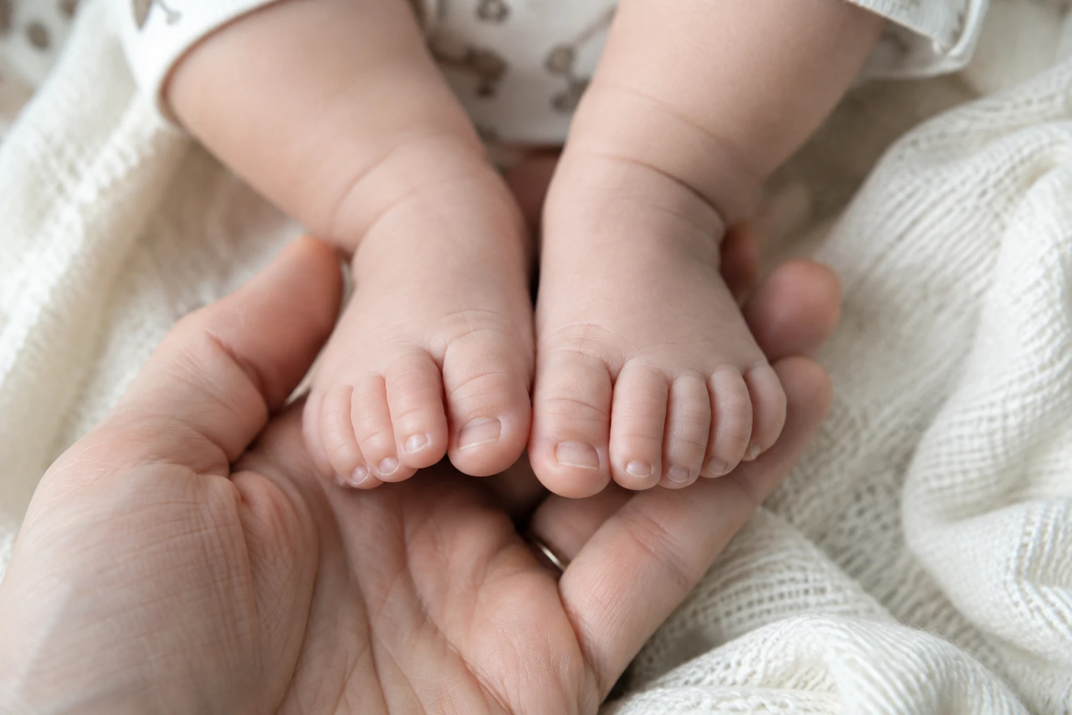 Baby’s toes resting in an adult hand